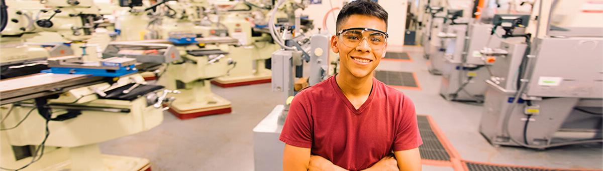 a student stands smiling in Pima's machine tooling class